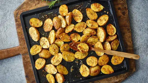 Goldbraune, knusprige Kartoffelspalten mit Rosmarin und Knoblauch, bereit für ein köstliches Ofenkartoffeln Rezept.