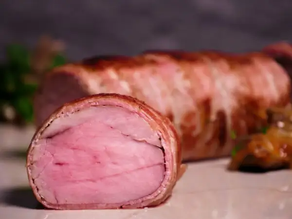 Perfekt gegartes sous-vide schweinefilet, umhüllt von knusprigem Speck. Eine köstliche Beilage, die auf jeder sous-vide schweinefilet tabelle glänzt.
