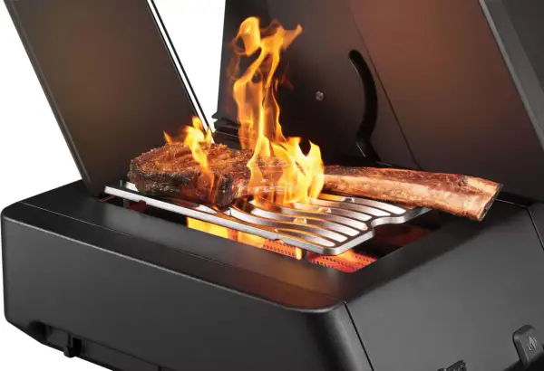 Zwei saftige Steaks brutzeln in der Sizzle Zone des Grills, umgeben von lodernden Flammen.