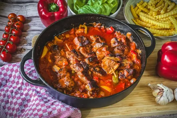 Herzhaftes Schaschlik im Backofen, geschmort in einer würzigen Tomatensoße mit Paprika und Zwiebeln. Dazu passen Pommes und frischer Salat.